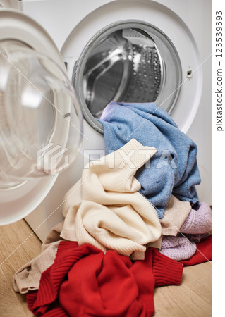 Colorful and white wool laundry and washing machine with open door. Close up. 123539393