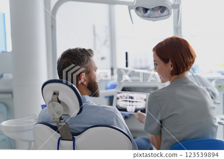 Female dentist showing x-ray to patient in dental clinic during anual check-up. Female dentist showing x-ray to patient in dental clinic during anual check-up. 123539894