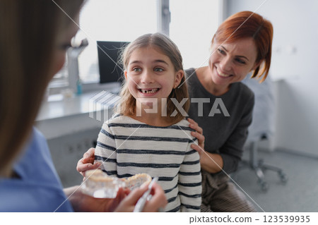 Girl showing her lost tooth to the dentist during a routine checkup at the dental clinic. 123539935