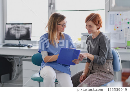 Patient talking with her female dentis during annual check up in dental clinic. 123539949