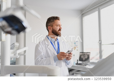 Portrait of handsome doctor in doctors office make phone call with patient. 123539950