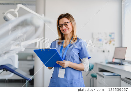 Friendly nurse a modern medical clinic looking at appointment schedule in clipboard. Friendly nurse a modern medical clinic looking at appointment schedule in clipboard. 123539967