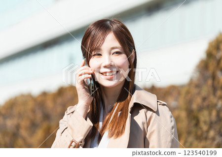 Image of a woman making a phone call outdoors (stock photo) Image of a woman making a phone call outdoors (stock photo) 123540199