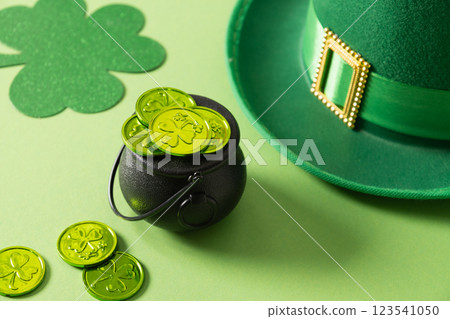 St Patricks day and March 17 concept of parade Leprechaun Hat with belt and green coins in black pot on green background. Close up. St Patricks day and March 17 concept of parade Leprechaun Hat with belt and green coins in black pot on green background. Close up. 123541050
