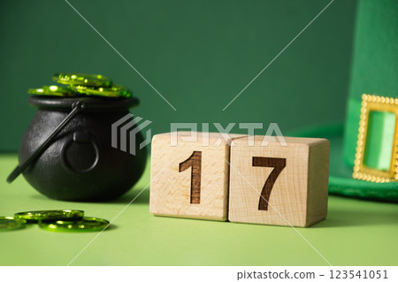St Patricks day concept with green Leprechaun Hat, coins in black pot, celebrate date at wooden block on green background. Close up. Copy space. St Patricks day concept with green Leprechaun Hat, coins in black pot, celebrate date at wooden block on green background. Close up. Copy space. 123541051