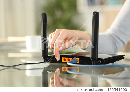 Woman hand reseting or turning on modem at home 123541300