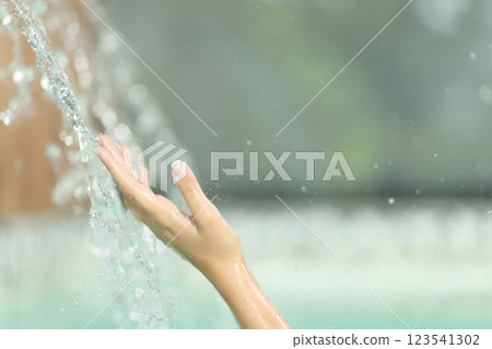 Woman hand touching water jet in spa pool Woman hand touching water jet in spa pool 123541302
