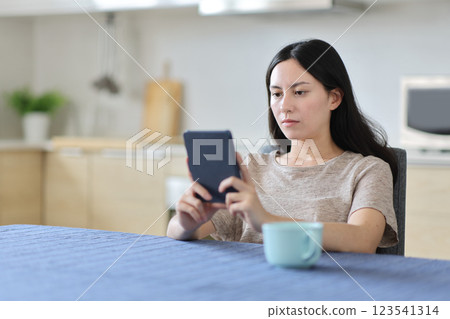 Asian woman reading an ebook in the kitchen at home 123541314