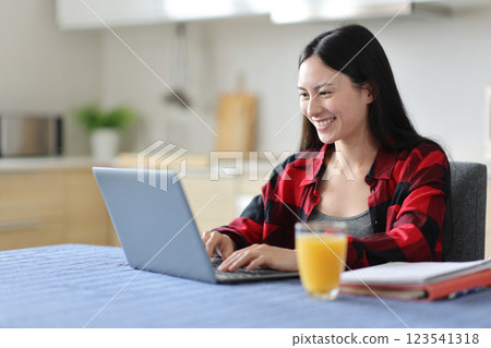 Happy asian student writing on laptop at breakfast 123541318