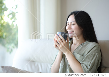 Happy asian woman smelling coffee aroma at home Happy asian woman smelling coffee aroma at home 123541325