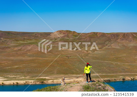 girl in a sports uniform with a dog in the mountains. woman with a husky on background of the steppe girl in a sports uniform with a dog in the mountains. woman with a husky on background of the steppe 123541539