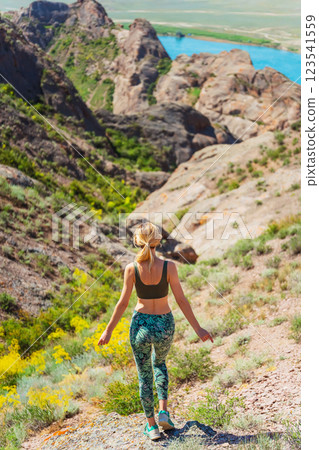 girl stands on a rock against the backdrop of the steppe. woman takes a break from running girl stands on a rock against the backdrop of the steppe. woman takes a break from running 123541559
