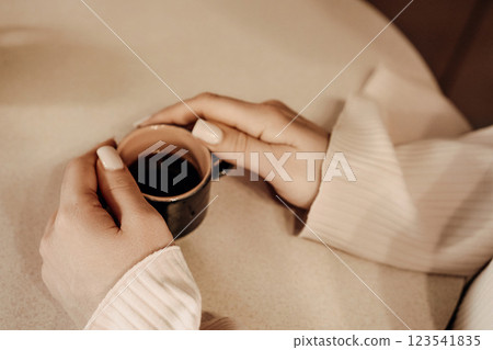 Coffee Hands Cozy: Woman enjoys espresso indoors, relaxing, warmth. 123541835