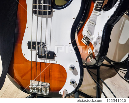 Guitars displayed on a stand in a music studio showcasing a bass guitar and an electric guitar during a daytime session Guitars displayed on a stand in a music studio showcasing a bass guitar and an electric guitar during a daytime session 123541910