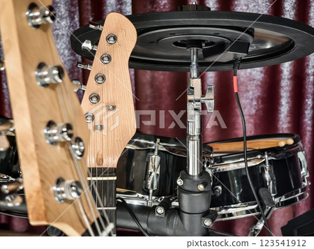 Close-up view of a guitar and electronic drum set in a music studio during a jam session Close-up view of a guitar and electronic drum set in a music studio during a jam session 123541912