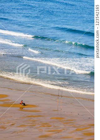Angler with fishing rod on sea shore Angler with fishing rod on sea shore 123542165