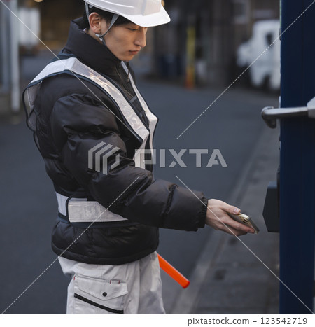 A man in work clothes drinking canned coffee A man in work clothes drinking canned coffee 123542719