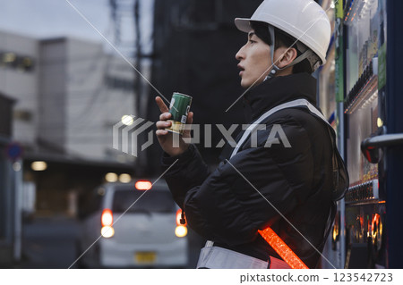 一名穿著工作服的男子正在喝罐裝咖啡 123542723