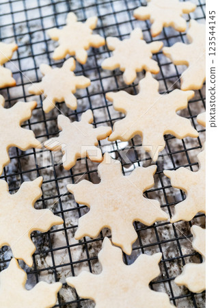 Letting delightful snowflake-shaped sugar cookies cool on a rack, preparing them for festive Christmas gifts. 123544145