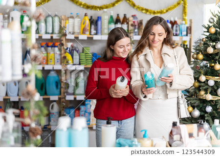 Woman with daughter choosing shampoo in festively decorated store 123544309