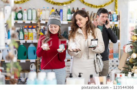 Teenage girl with mom choosing beauty products in holiday decorated store Teenage girl with mom choosing beauty products in holiday decorated store 123544366