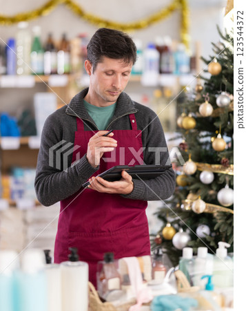 Male salesperson makes notes on an electronic tablet - keeps track of the receipt and expenditure of goods in supermarket Male salesperson makes notes on an electronic tablet - keeps track of the receipt and expenditure of goods in supermarket 123544372