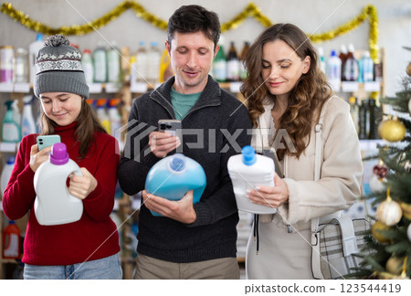 Couple man and woman with daughter scanning qr code for detergent Couple man and woman with daughter scanning qr code for detergent 123544419