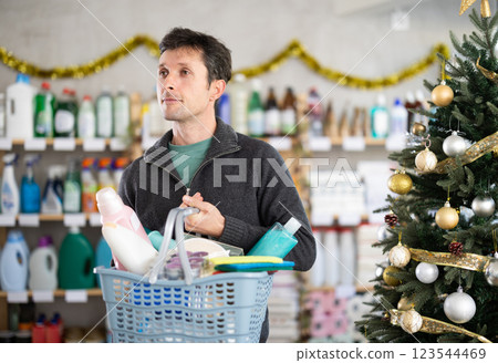Man buyer with filled basket household chemistry wanders around store 123544469