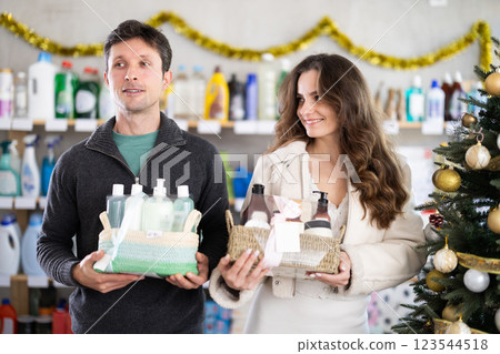 Couple choosing gift sets with self-care products at Christmas decorated store Couple choosing gift sets with self-care products at Christmas decorated store 123544518