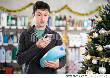 Checking expiration date of detegrent - male shopper scans QR code on label of detegrent using smartphone Checking expiration date of detegrent - male shopper scans QR code on label of detegrent using smartphone 123544524