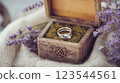 Wedding rings with gemstone resting in rustic wooden box with lavender sprigs 123544561