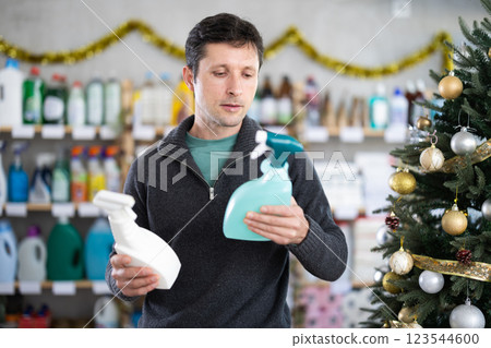 Adult man chooses cleaning spray in decorated store 123544600