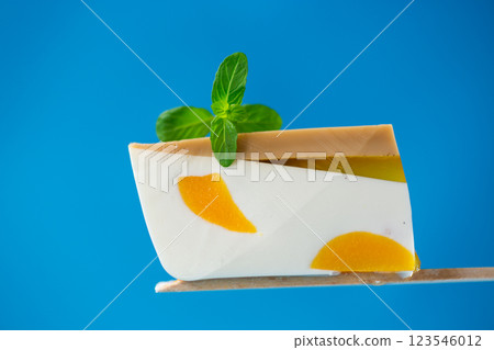 piece of milk fruit jelly with pieces of fruit inside on blue background 123546012