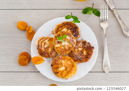 Cottage cheese pancakes with dried apricots and honey on a wooden table Cottage cheese pancakes with dried apricots and honey on a wooden table 123546027