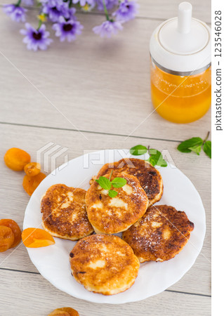 Fresh cottage cheese pancakes with pieces of dried apricots and a leaf of mint Fresh cottage cheese pancakes with pieces of dried apricots and a leaf of mint 123546028