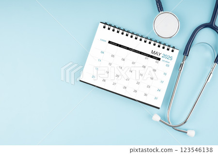 May 2025 desk calendar and stethoscope on blue, Position with copy space. 123546138