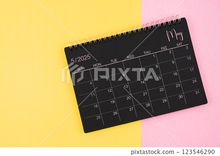 May 2025 Black calendar spiral on yellow and pink background. May 2025 Black calendar spiral on yellow and pink background. 123546290