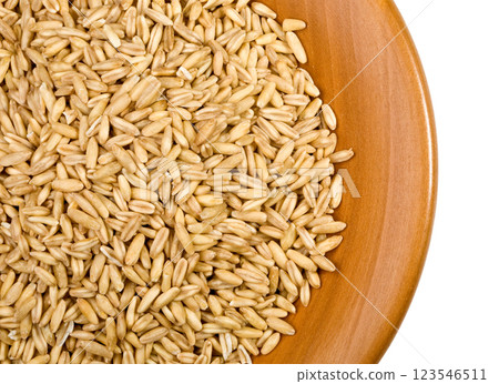 Oat groats filling a wooden bowl on white background Oat groats filling a wooden bowl on white background 123546511
