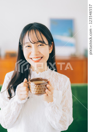A woman sitting on a sofa and drinking coffee A woman sitting on a sofa and drinking coffee 123546557