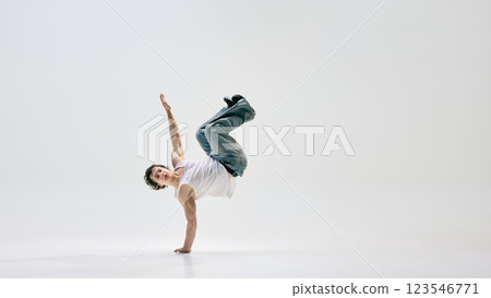 Street performer shifting into backbend freeze, embodying power and technical precision against white background. Concept of dance and music 123546771