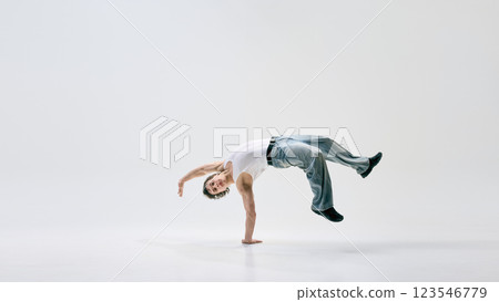 Street performer flipping effortlessly with sharp body control expressing passion through movement against white background. Street performer flipping effortlessly with sharp body control expressing passion through movement against white background. 123546779