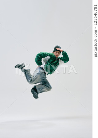Urban dancer dressed retro attire, jumps with arms stretched and legs bent in midair in motion against white studio background. Urban dancer dressed retro attire, jumps with arms stretched and legs bent in midair in motion against white studio background. 123546781