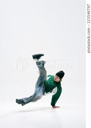 Urban dancer, dressed vintage, executing acrobatic spin, defying gravity with precision against white background. Dance and music. Urban dancer, dressed vintage, executing acrobatic spin, defying gravity with precision against white background. Dance and music. 123546797