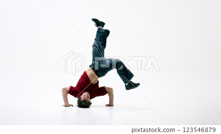 Breakdancer executing headstand freeze against white background, body arched, one leg kicked high, strength and balance in action. 123546879