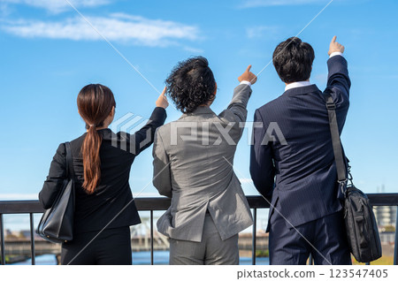 Three businessmen standing side by side and pointing at the sky Three businessmen standing side by side and pointing at the sky 123547405