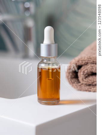 Dropper bottle with pipette near brown towels on basin in tropical bathroom close up cosmetic mockup 123548098