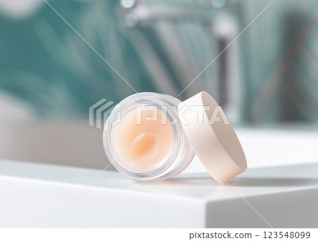 Opened white blank lip balm jar on wash basin in green tropical bathroom close up, cosmetic mockup Opened white blank lip balm jar on wash basin in green tropical bathroom close up, cosmetic mockup 123548099