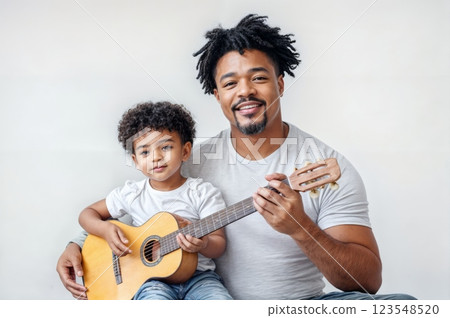 Father teaches son to play guitar while sharing a joyful moment in a bright room 123548520