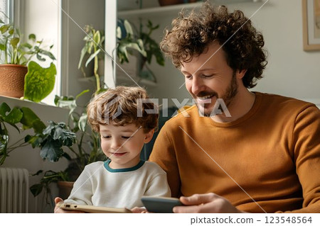 Father and son enjoy quality time together while engaging with digital devices indoors 123548564