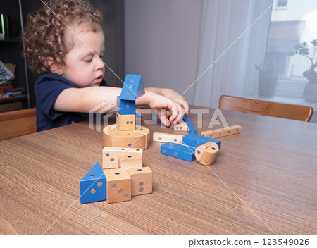 Little boy play with wooden on magnets constructor at home on table. Children and educational games. Little boy play with wooden on magnets constructor at home on table. Children and educational games. 123549026